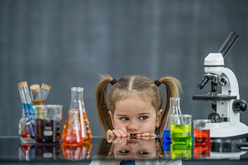 Curious girl looking at science beakers