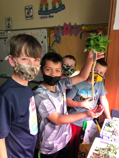 Students displaying a plant grown in class..