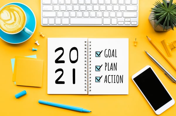 Goal Plan Action 2021 planner on a desk, surrounded by supplies